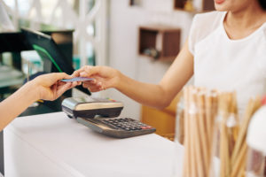 Une femme donne sa carte à uen barista pour payer un café